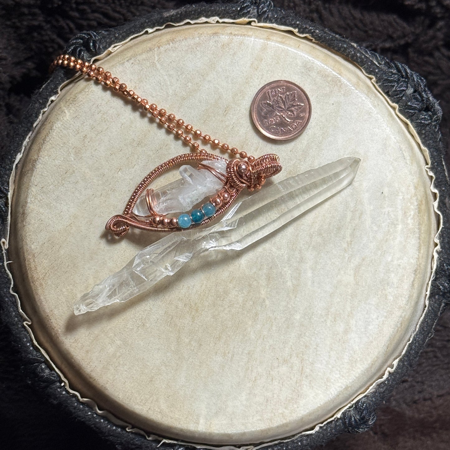 Display view of a Lemurian crystal pendant in raw copper with blue apatite accents, shown with clear crystal points and a 22 inch copper ball chain.
