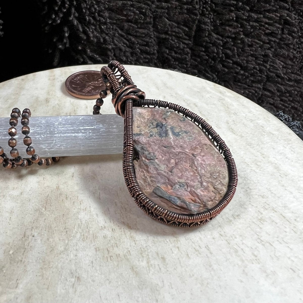 Back view of ammonite fossil pendant showing natural stone texture and copper wire setting