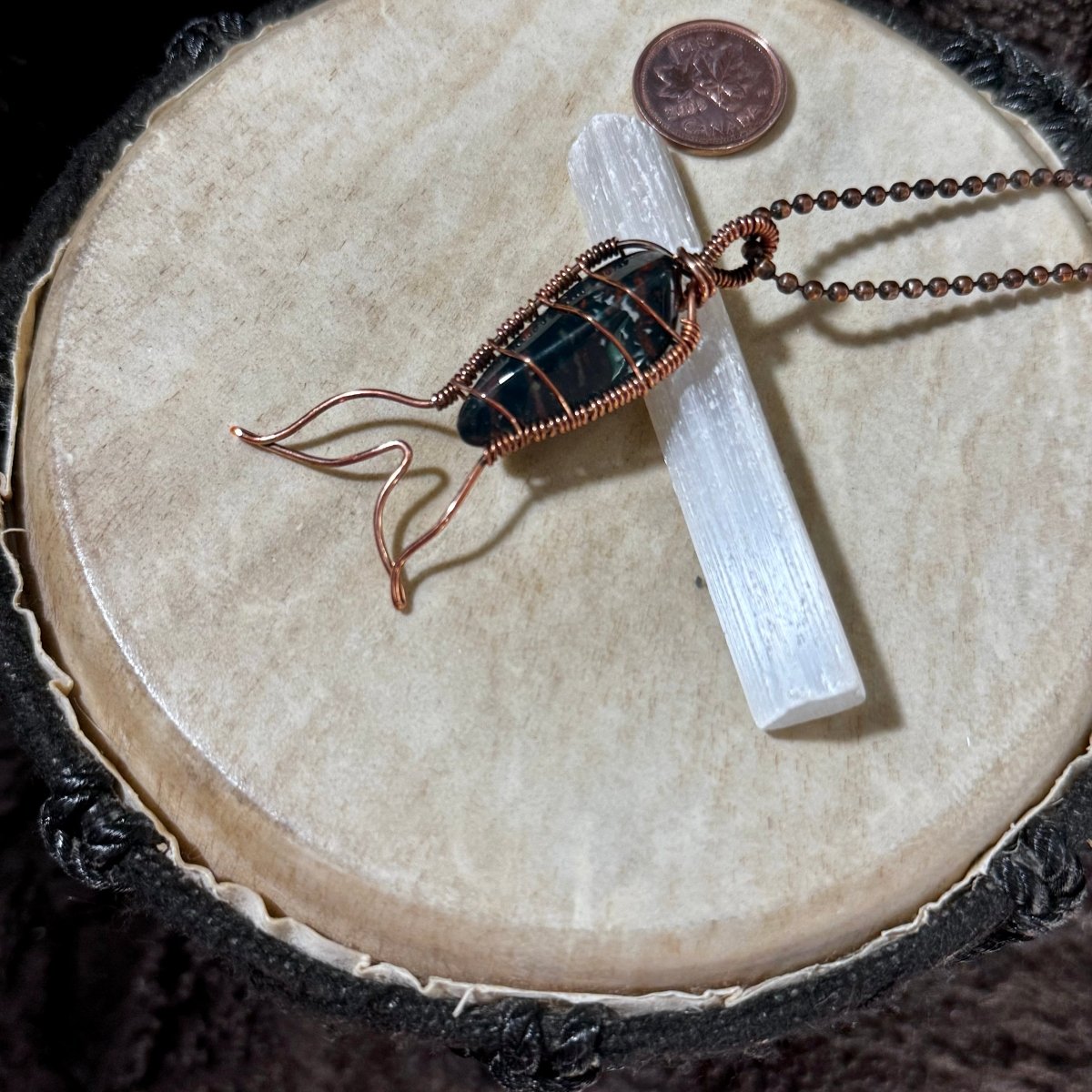Side view of a handcrafted Bay of Fundy Bloodstone Mermaid Tail Necklace showcasing reclaimed copper wire wrapping and the flowing mermaid tail design.