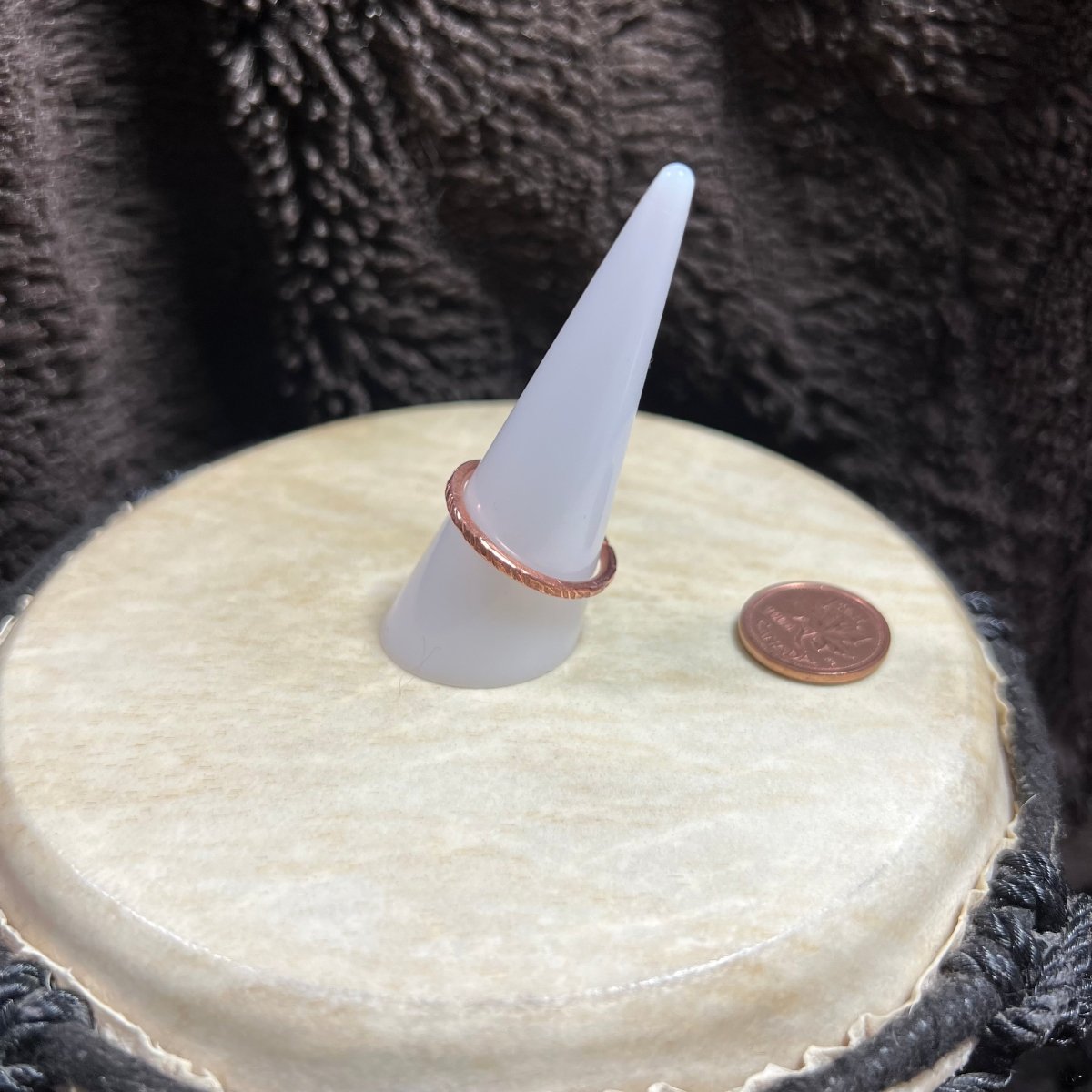 White cone-shaped object with a copper ring on a textured surface