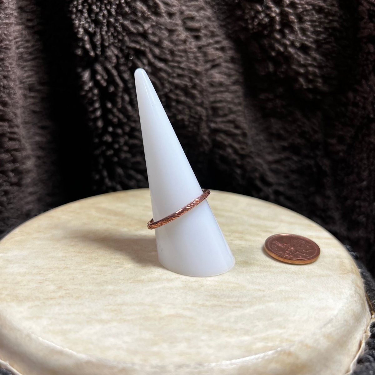 White cone-shaped object with a copper ring on a textured surface