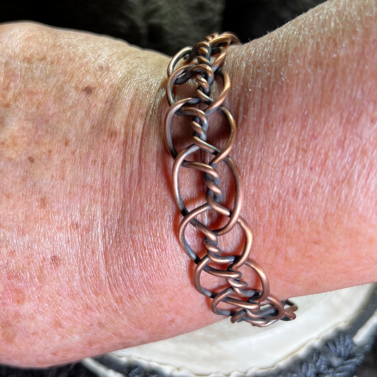 Close-up of a person's wrist wearing a copper chain bracelet.