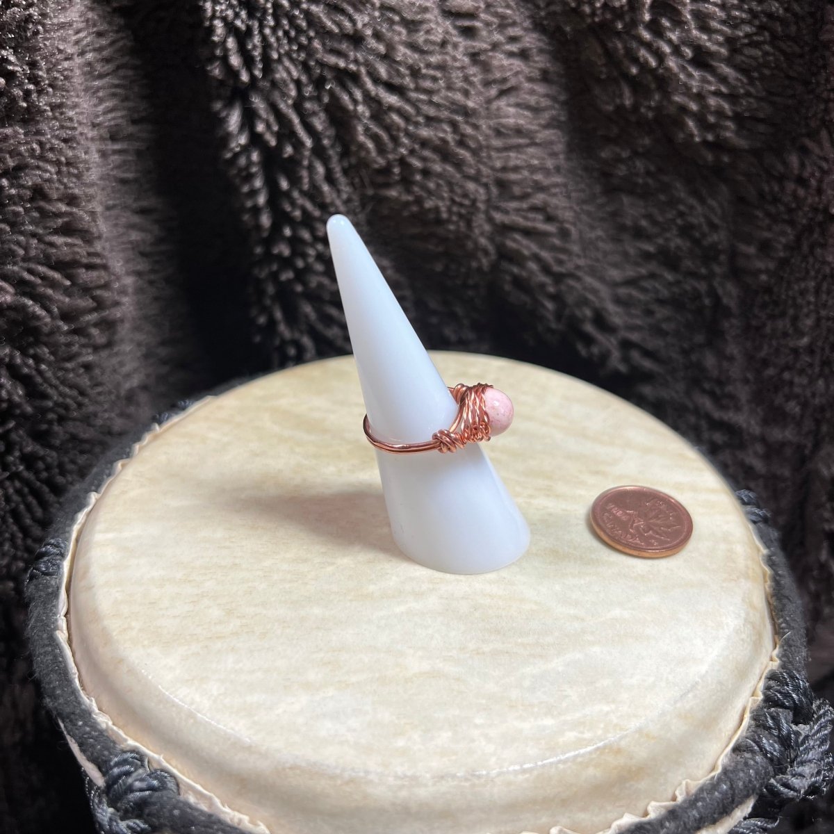 White cone-shaped jewelry stand with a ring on a textured surface