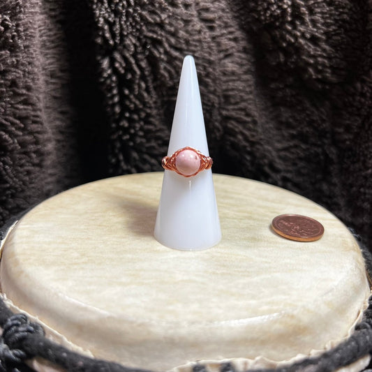 White cone-shaped jewelry stand with a ring on a textured surface