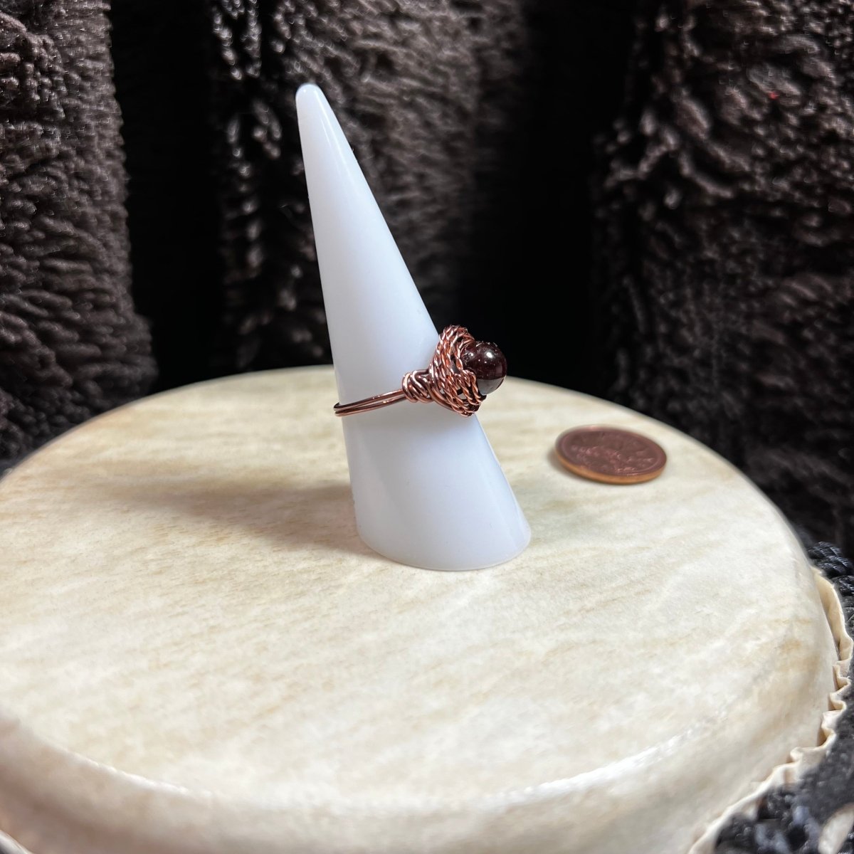 Ring on a white cone-shaped stand with a dark textured background