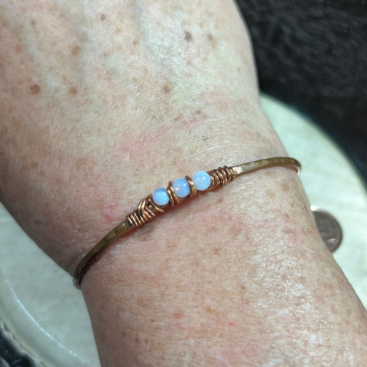 Copper bracelet with three blue lace agate beads on a wrist.