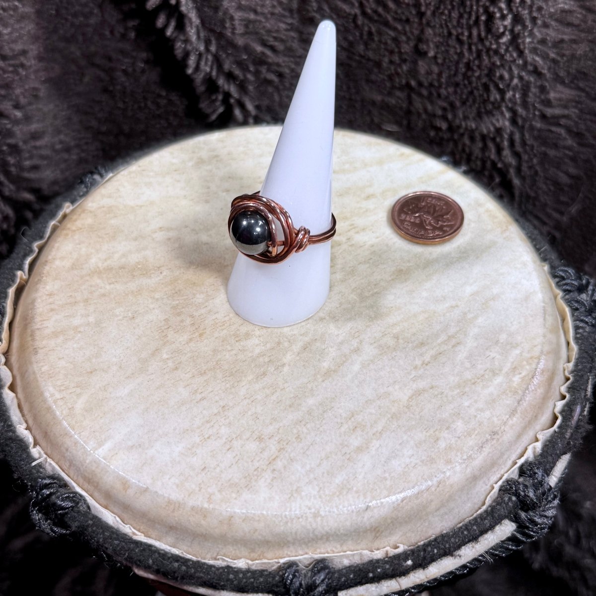 Side view of a handmade hematite and reclaimed copper ring showing its raised spherical stone and secure circular wirework.