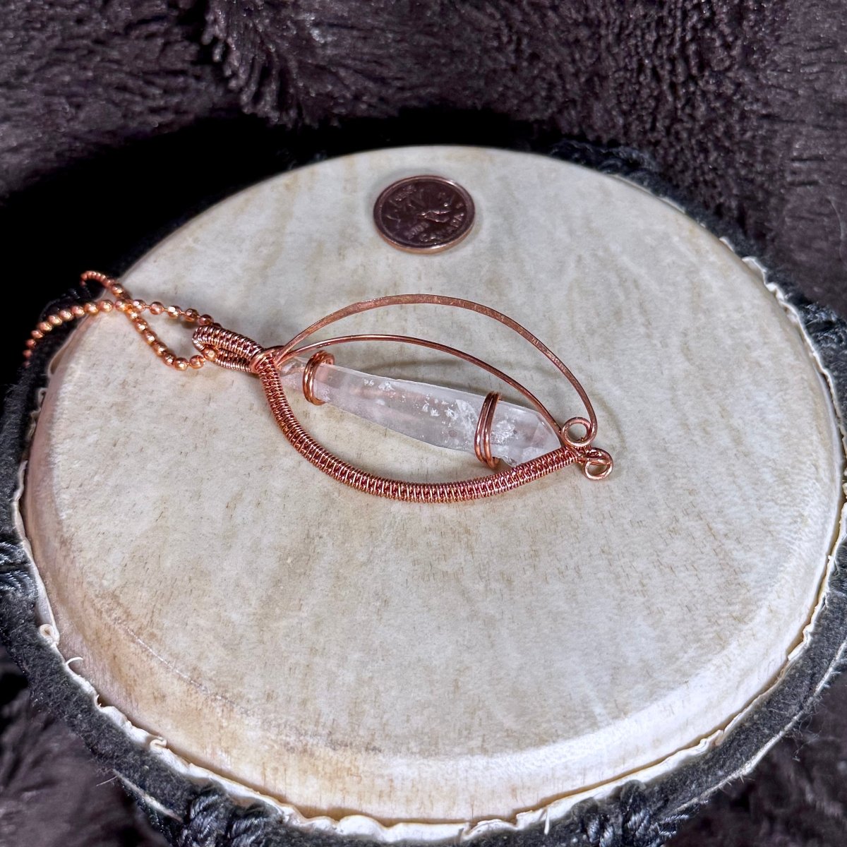 Angled close-up of the natural Lemurian Quartz point, internal veils and flowing reclaimed-copper arcs in this one-of-a-kind necklace.