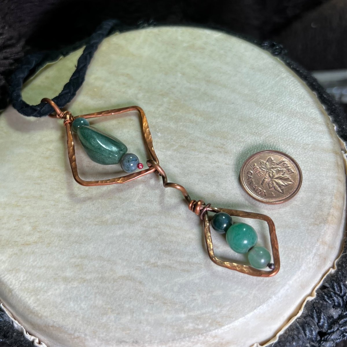 Diamond Motif necklace with moss agate stones and copper accents on a round beige surface.