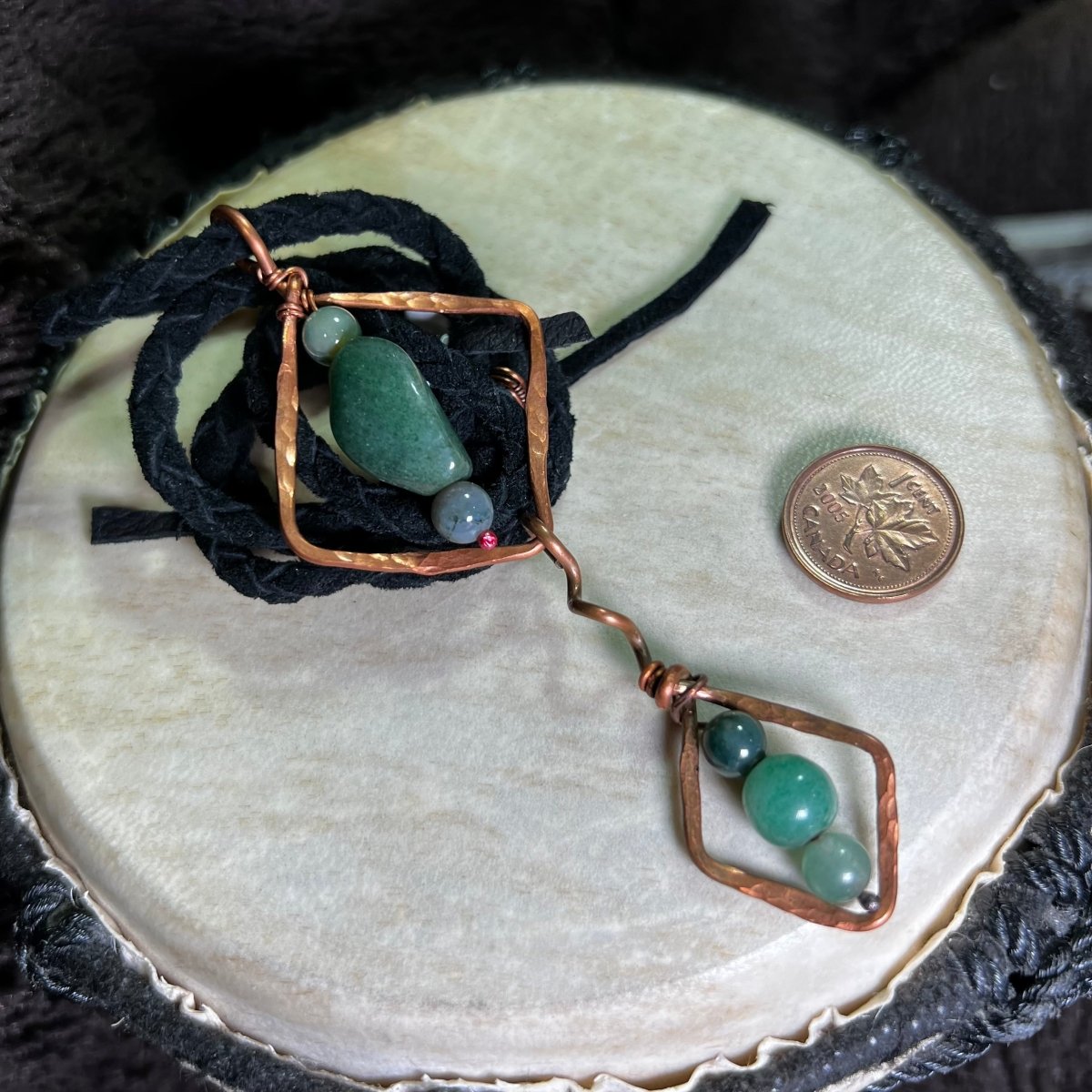 Diamond Motif necklace with moss agate stones and copper accents on a round beige surface.