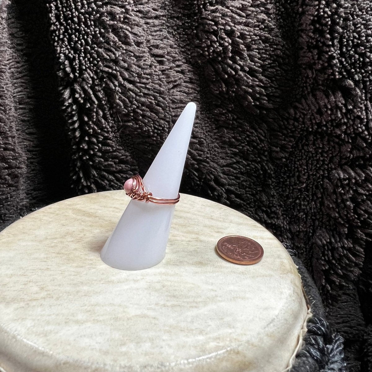 White cone-shaped object with a ring on top, placed on a textured surface.