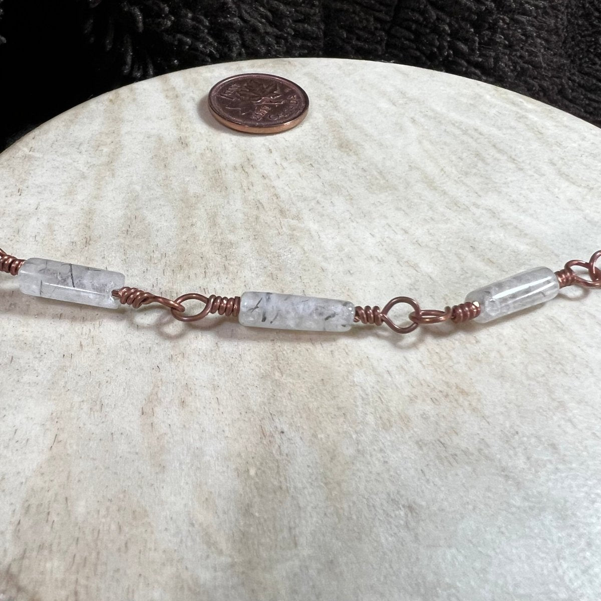 Close-up of tourmalinated quartz crystal bracelet with copper wire wrapping, artisan gemstone jewelry by Mother of Metal