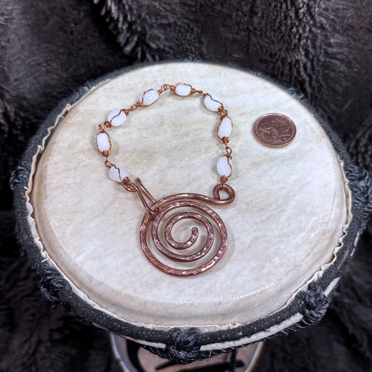 Fastened white moonstone and reclaimed copper bracelet featuring a bold hand-forged spiral focal and linked gemstone beads.