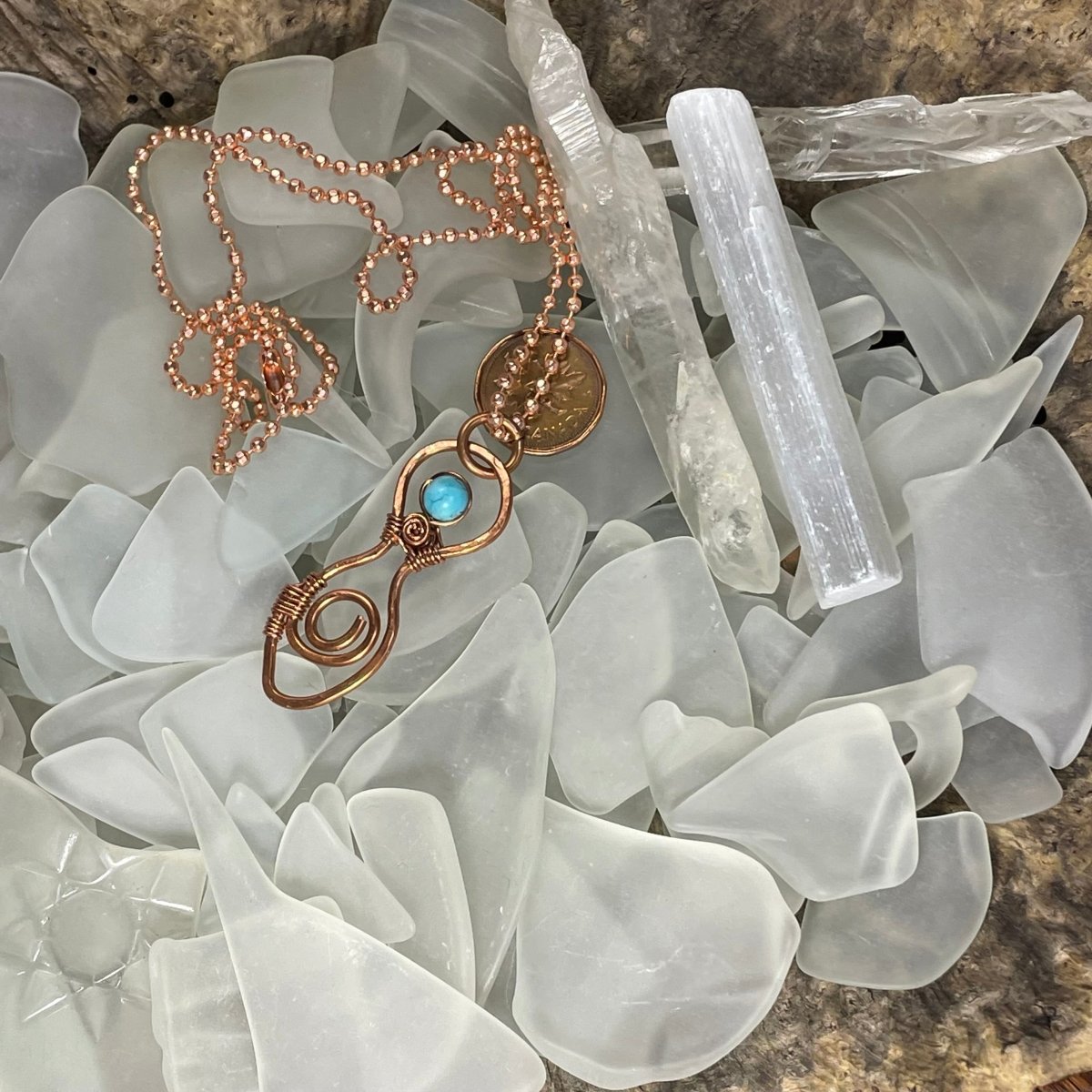 Spiral Goddess Necklace nestled in a bed of white sea glass