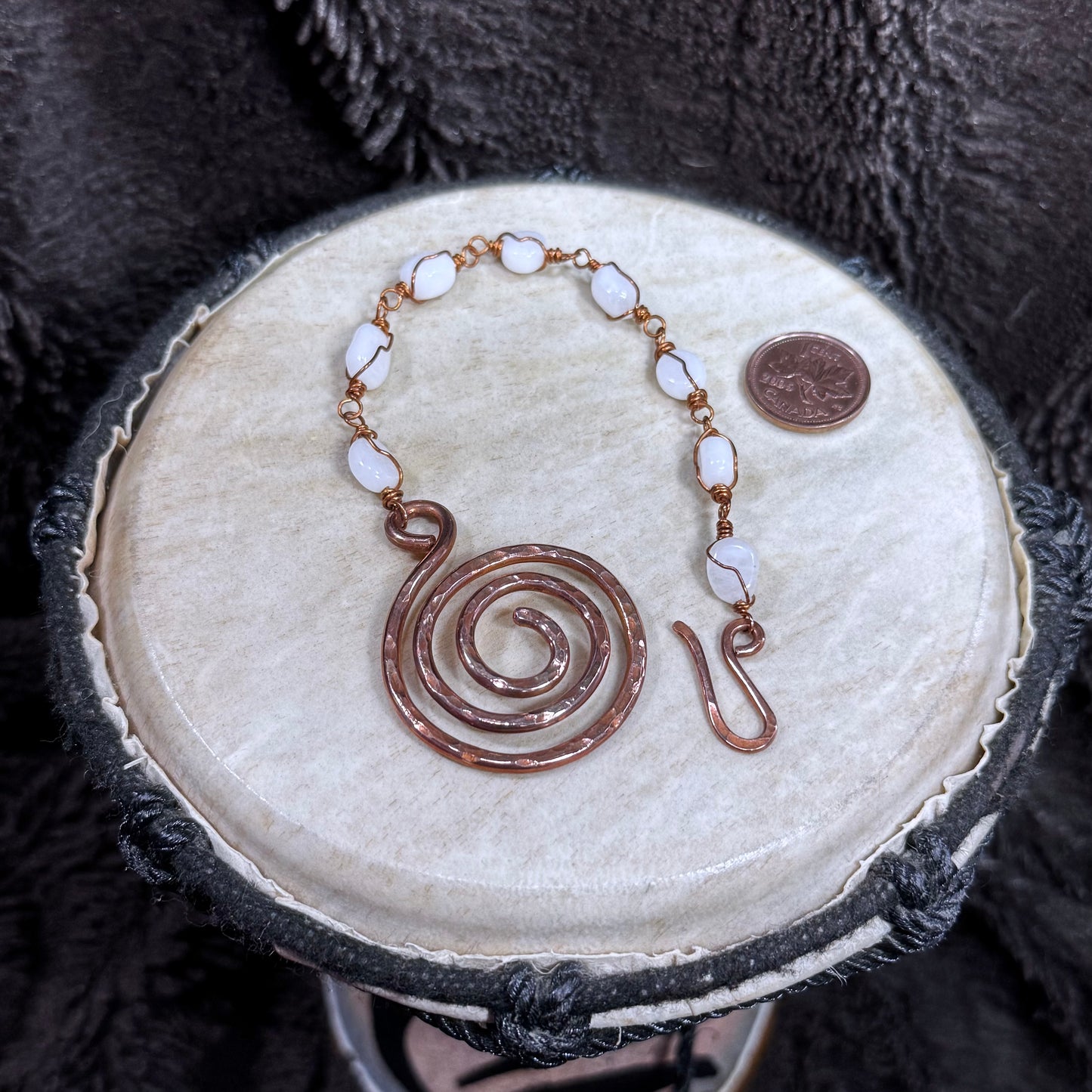 Open white moonstone bracelet with individually wire-wrapped stones, a large hammered spiral focal and handmade hook closure in reclaimed copper.