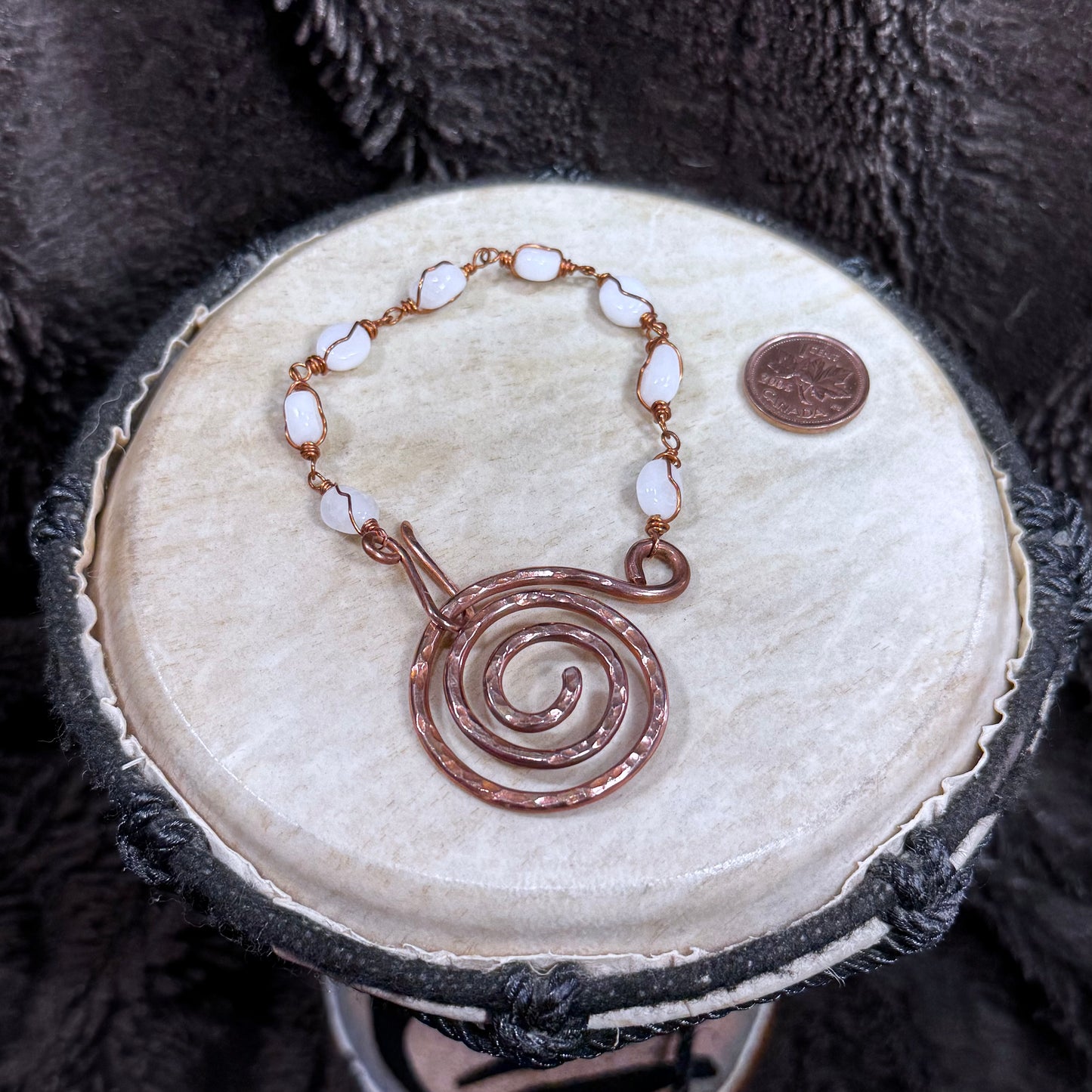 Fastened white moonstone and reclaimed copper bracelet featuring a bold hand-forged spiral focal and linked gemstone beads.