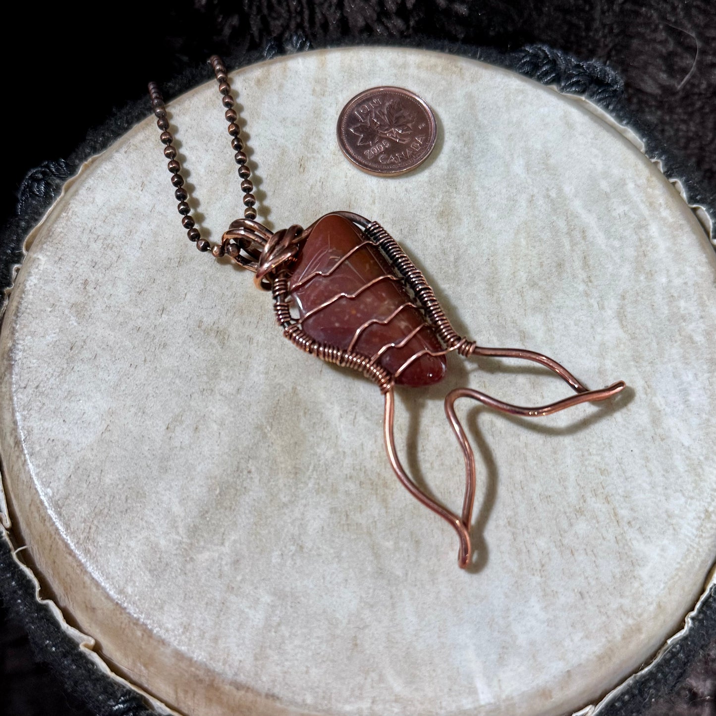 Handmade Red Jasper Mermaid Tail pendant wrapped in reclaimed copper, featuring a rich red natural gemstone with subtle banding and a flowing mermaid tail design.