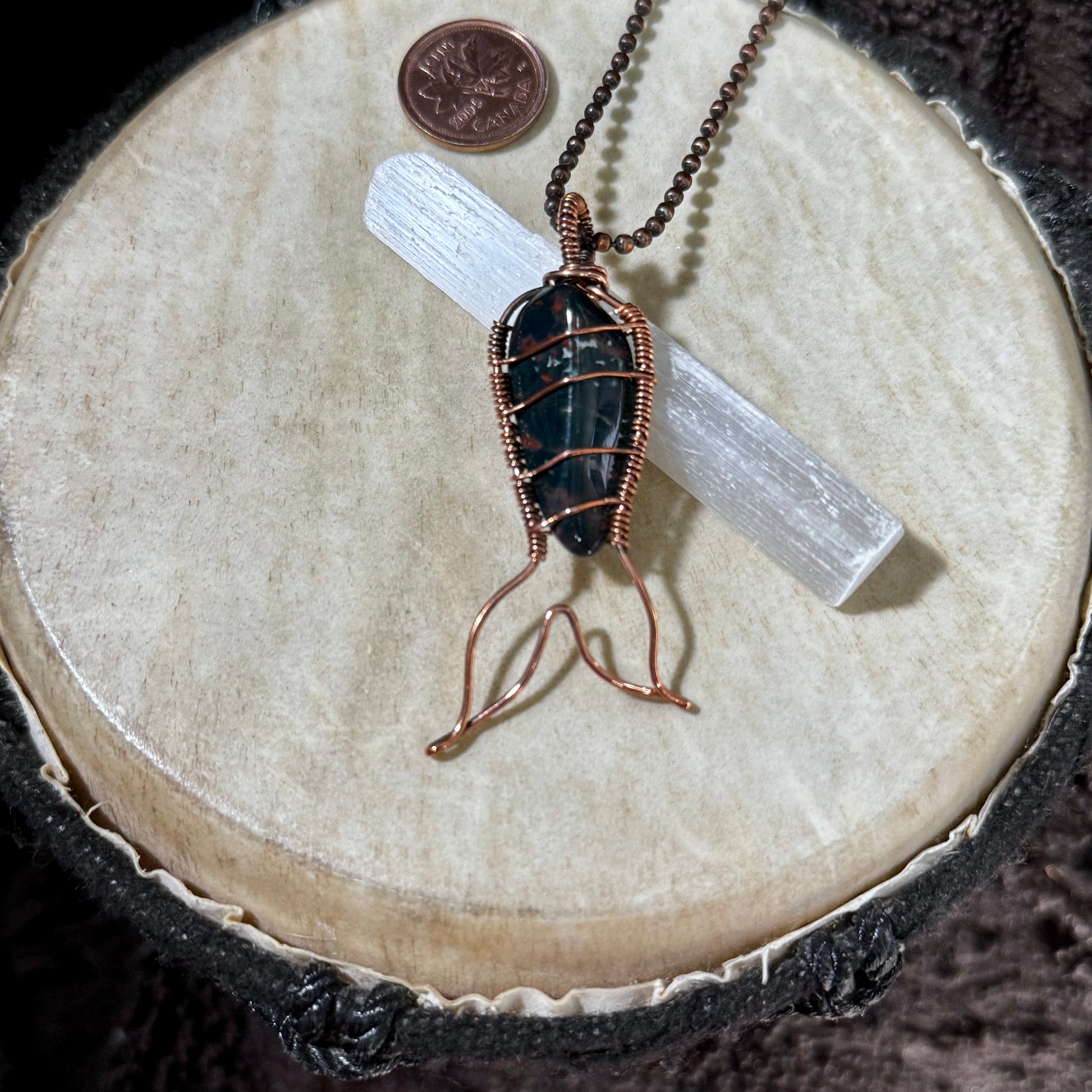 Handmade Bay of Fundy Bloodstone Mermaid Tail Necklace wrapped in reclaimed copper, featuring a dark green gemstone with natural red markings inspired by the rugged coastline of New Brunswick.