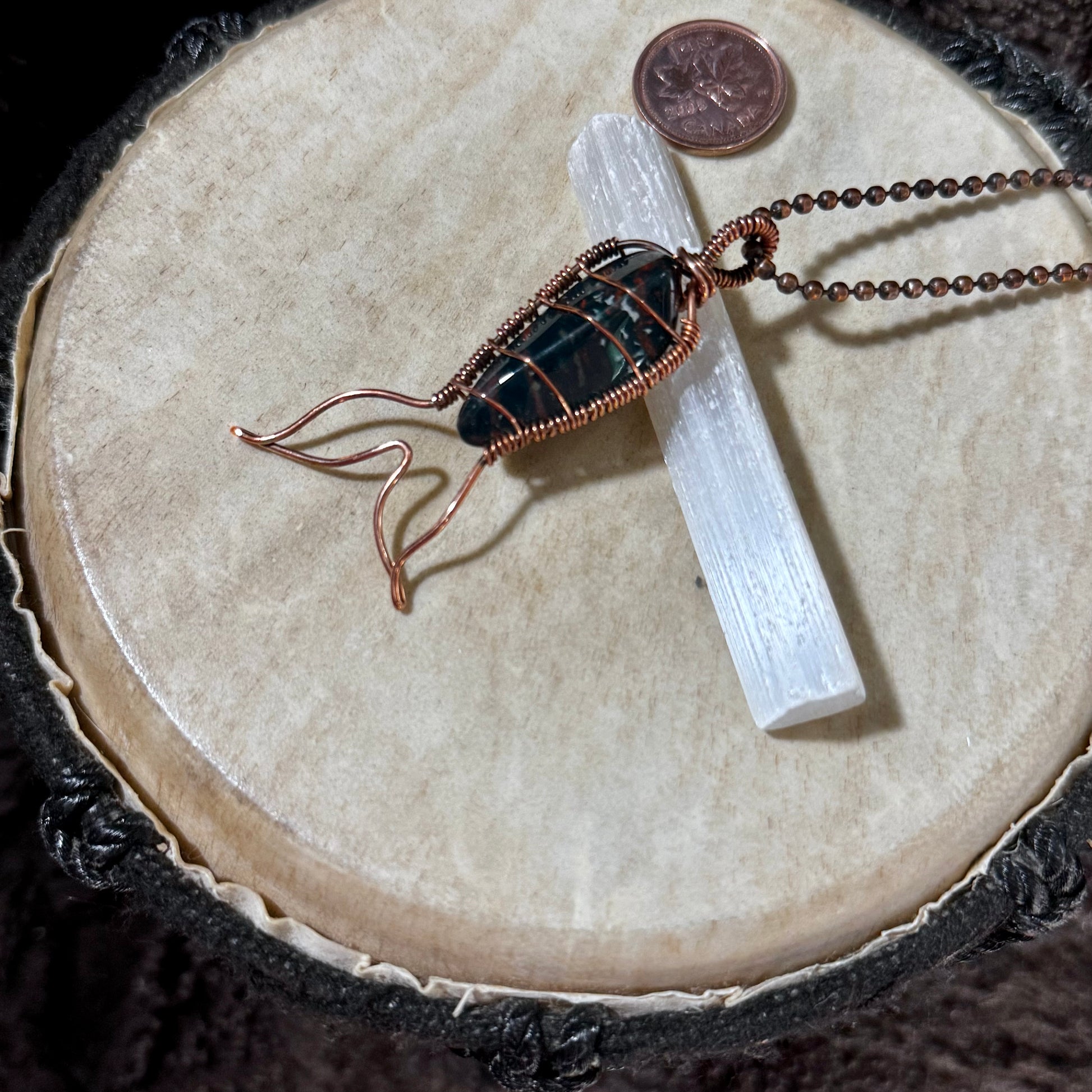 Side view of a handcrafted Bay of Fundy Bloodstone Mermaid Tail Necklace showcasing reclaimed copper wire wrapping and the flowing mermaid tail design.