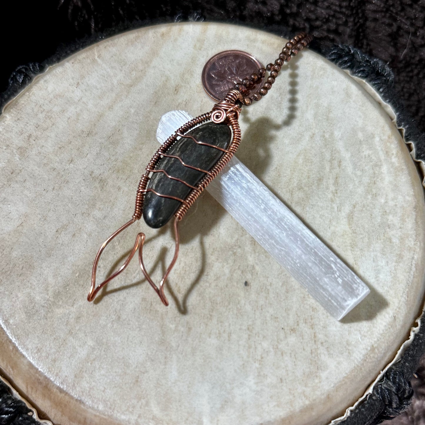Side angle of a reclaimed copper Mermaid Tail necklace featuring a naturally banded black agate collected from the Bay of Fundy.