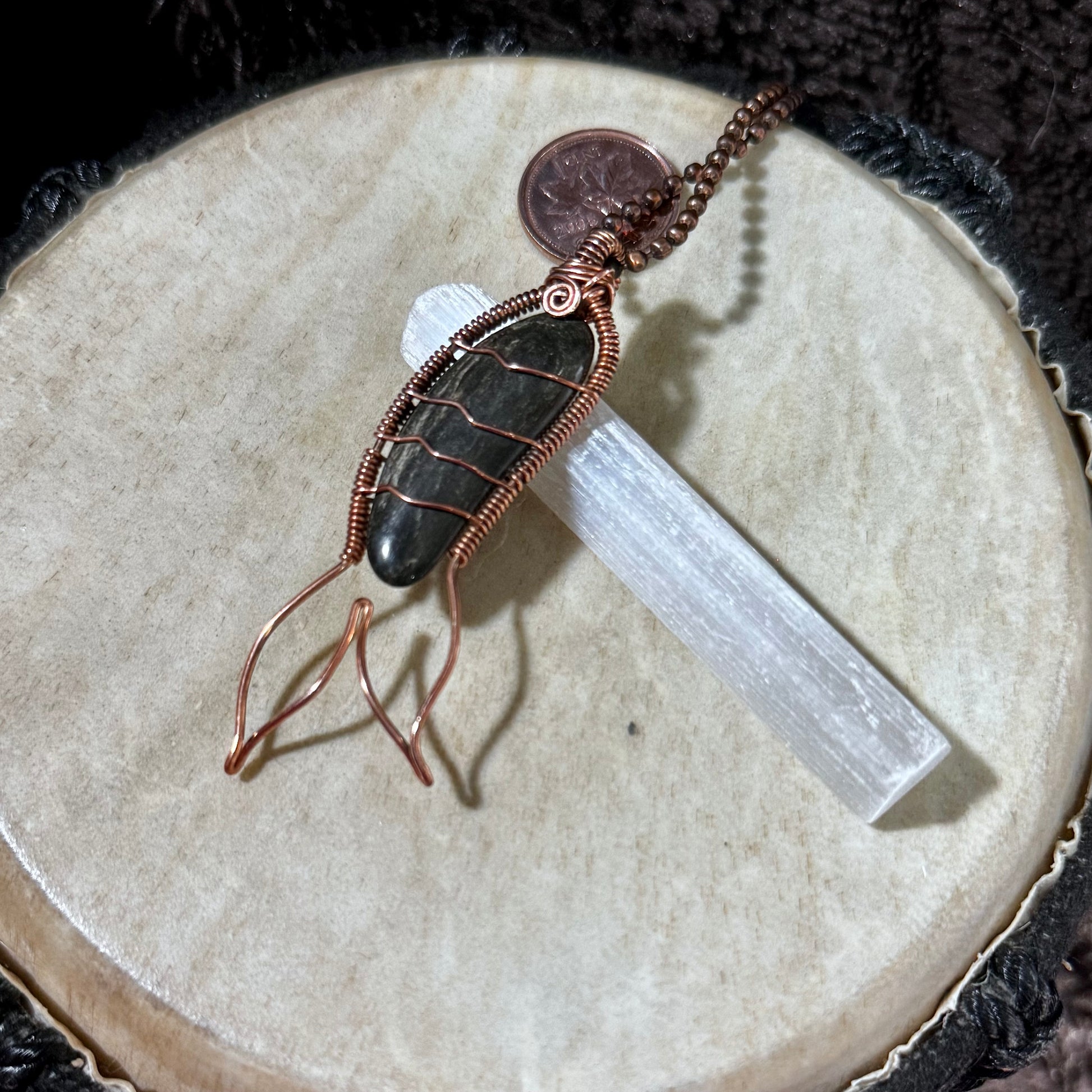 Side angle of a reclaimed copper Mermaid Tail necklace featuring a naturally banded black agate collected from the Bay of Fundy.