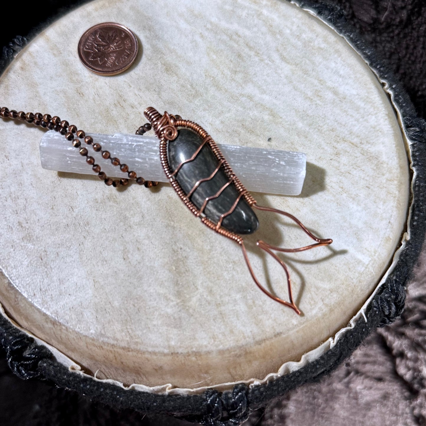 Profile view highlighting the polished black agate cabochon, reclaimed copper wire wrapping and flowing Mermaid Tail design.