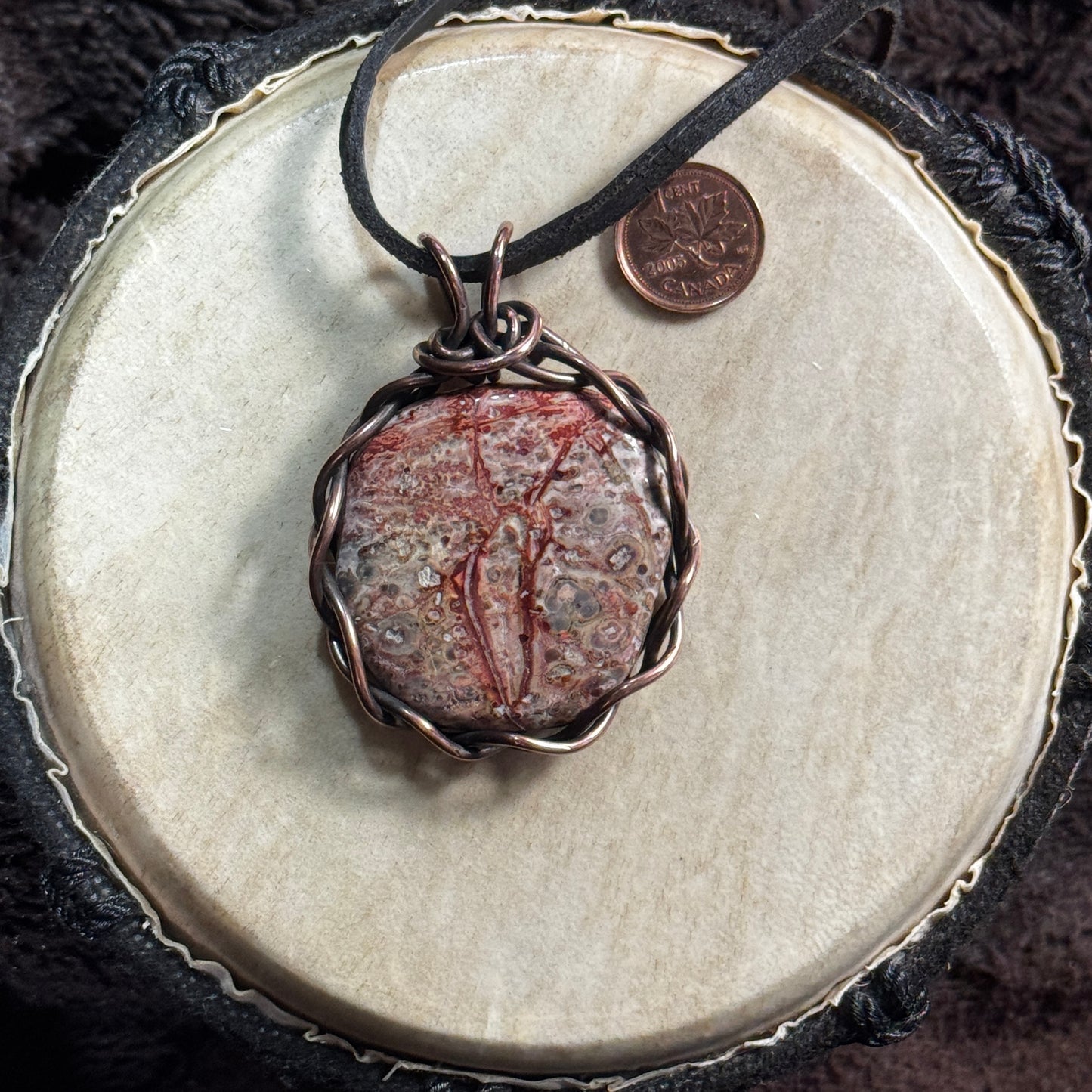 Front view of a handmade Leopardskin Jasper necklace wrapped in reclaimed patinated copper and suspended on reclaimed leather.
