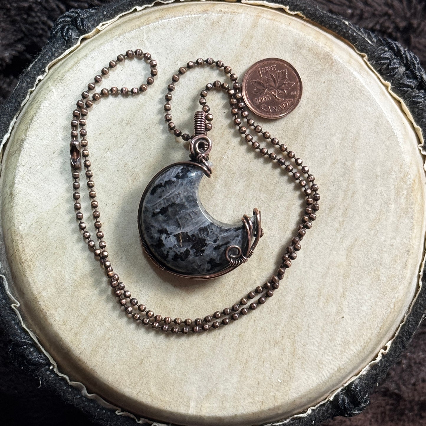 Front view of a handmade larvikite crescent moon necklace in patinated copper on a faceted copper ball chain.