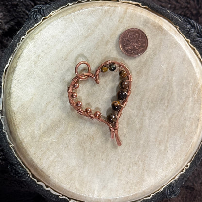 Alternate front view of a hand-planished raw copper heart pendant featuring yellow tiger's eye beads and raw copper bead details.