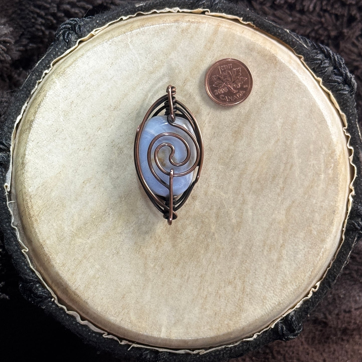 Reverse of a two-way blue lace agate pendant showing a bold copper spiral, patinated Herringbone frame and bails positioned at both ends.