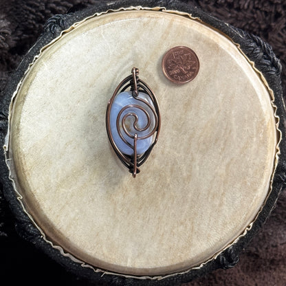 Reverse of a two-way blue lace agate pendant showing a bold copper spiral, patinated Herringbone frame and bails positioned at both ends.