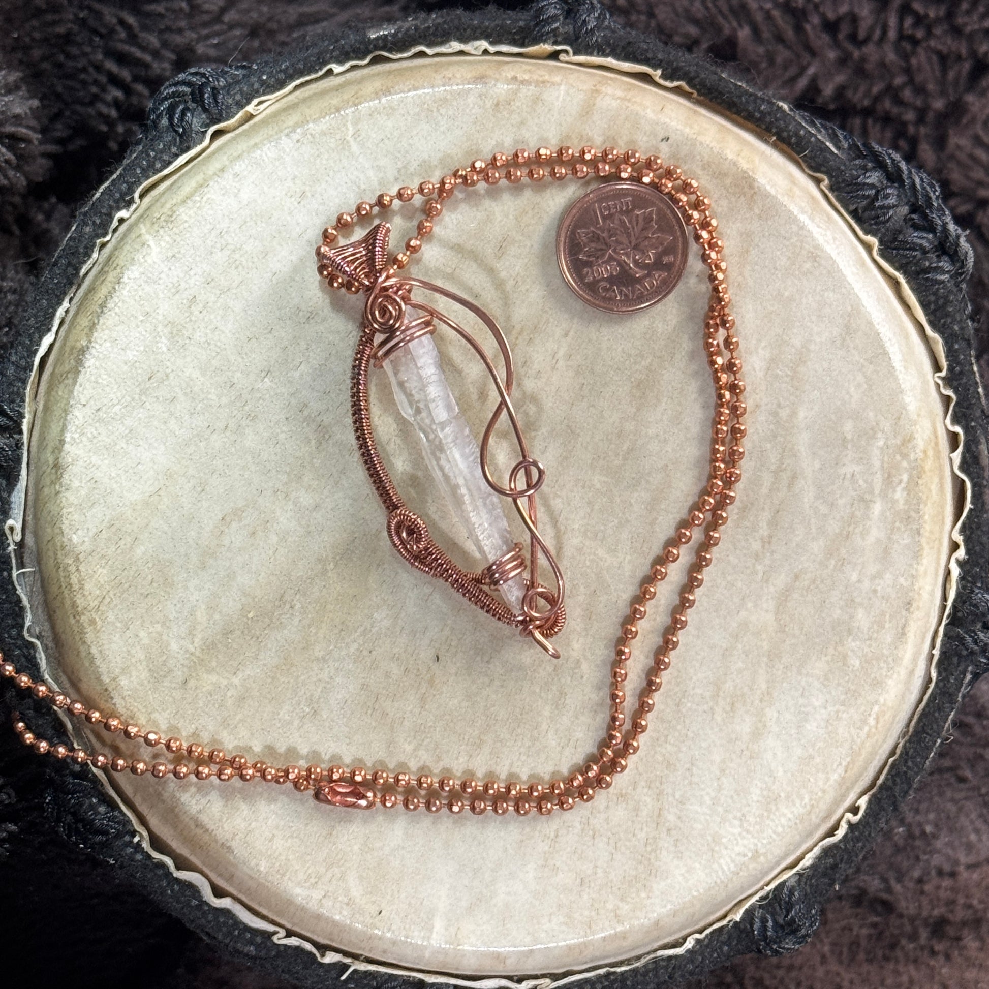 Lemurian quartz point held inside an open raw copper weave on a 21-inch faceted ball chain, with a Canadian penny shown for scale.