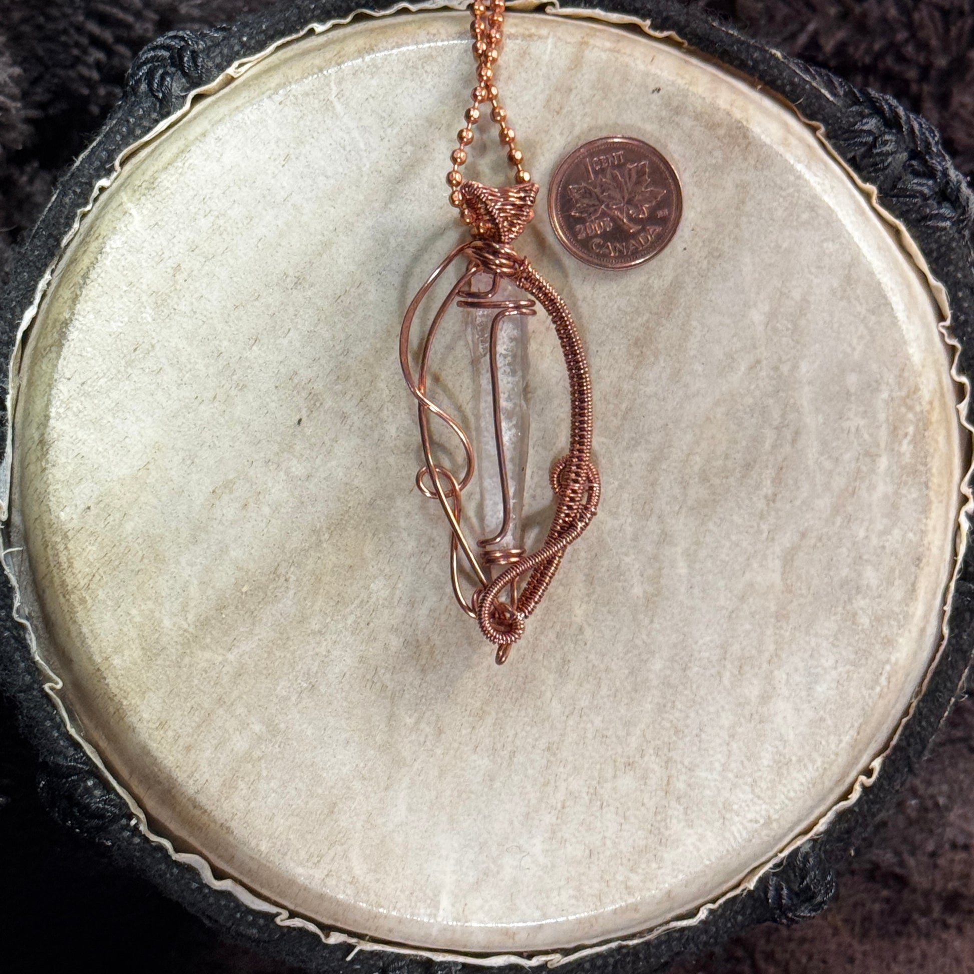 Alternate face of a Lemurian quartz necklace showing the crystal’s striations, sweeping open copper lines and tightly woven protective arc.