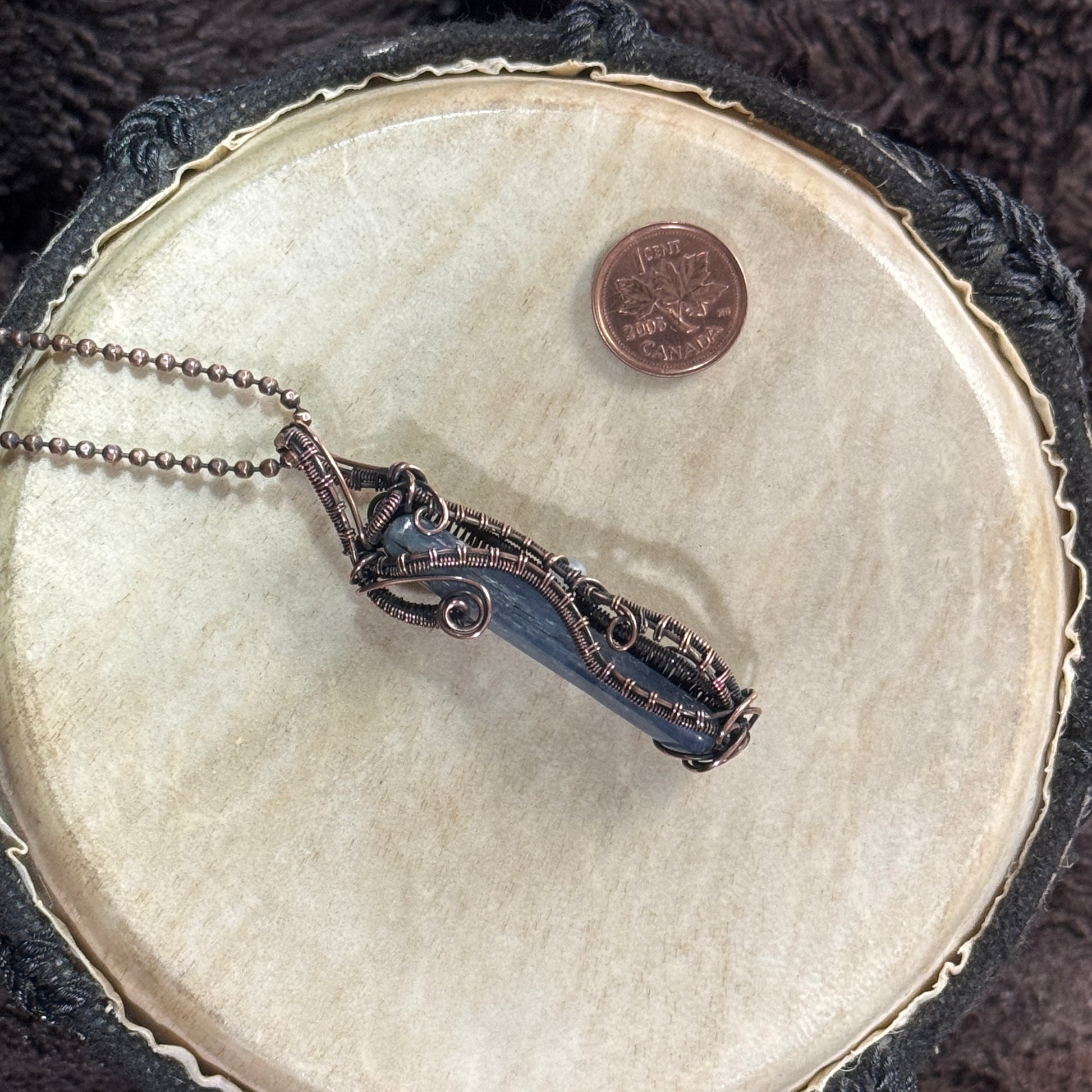 Side one of a reversible polished blue kyanite necklace with patinated copper spirals, woven borders and a streamlined unisex design.