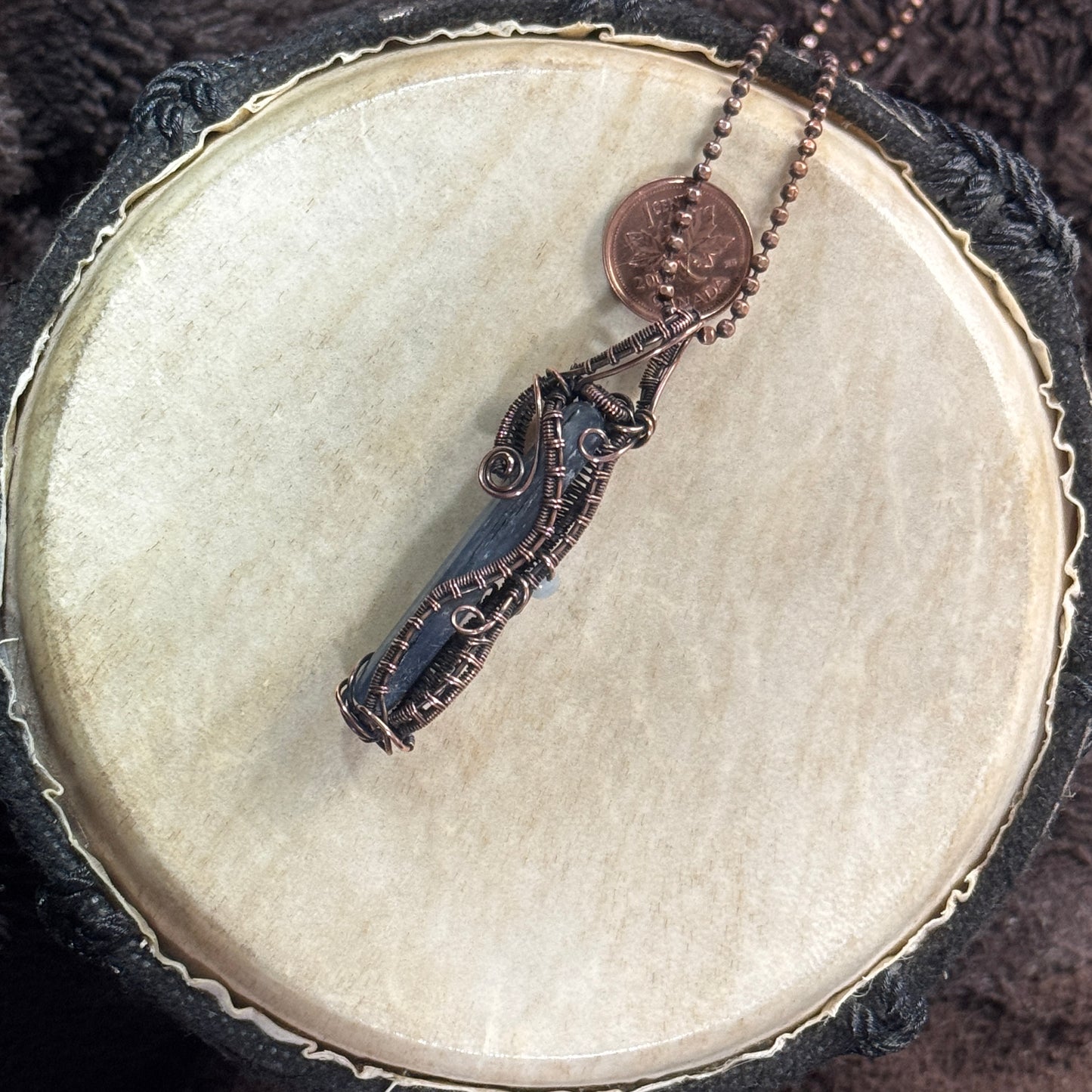 Alternate angled view of a reversible blue kyanite necklace showing its aquamarine accents, copper spirals and detailed woven framework.