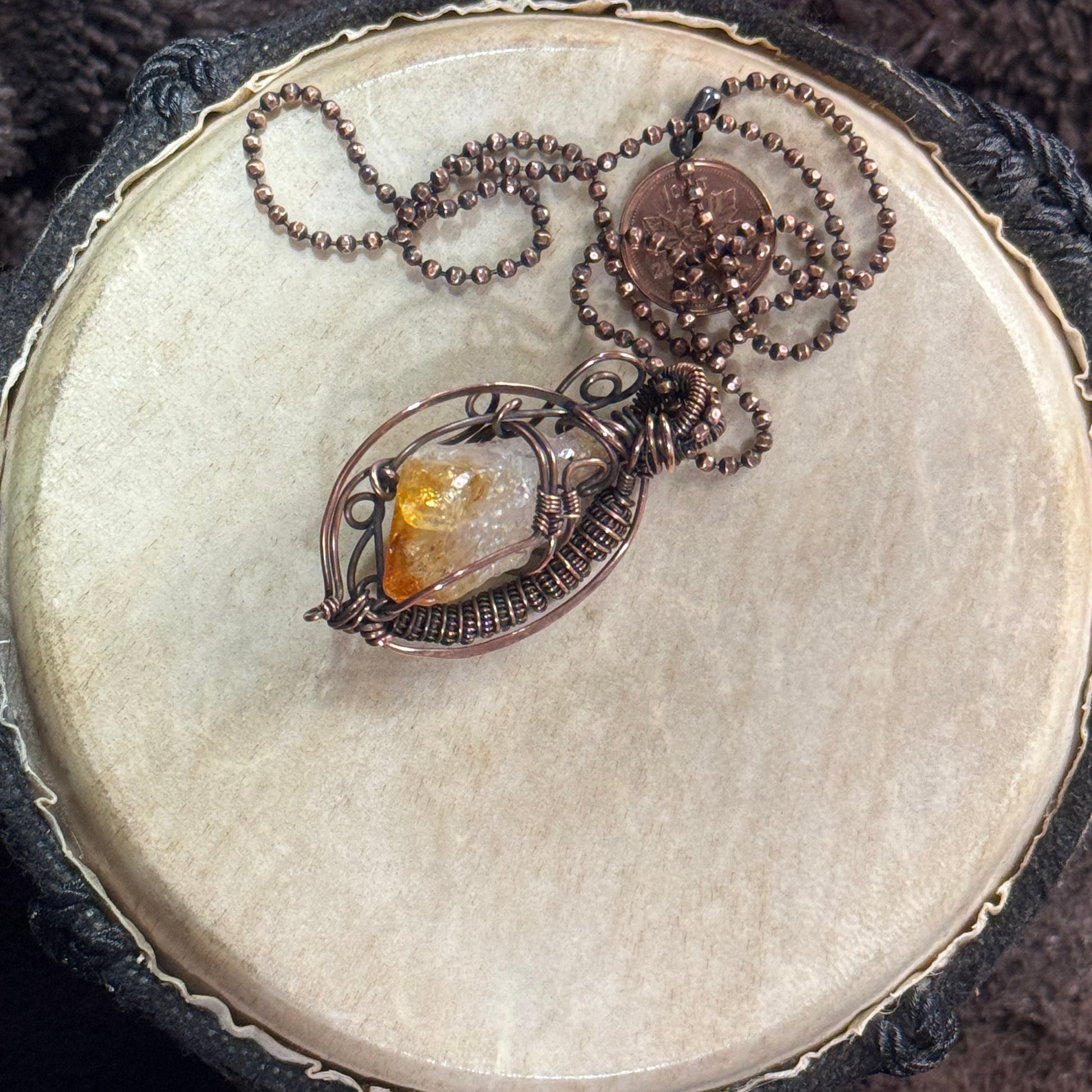 Reverse view of a raw citrine point showing its honey-gold tip, natural crystal texture and open sculptural patinated copper framework.