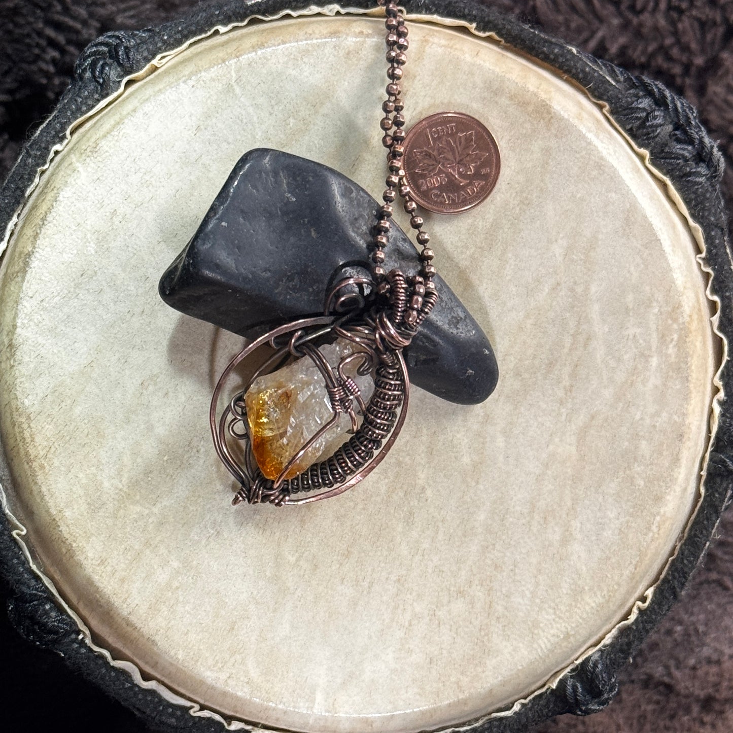 Alternate styled view of a raw citrine point necklace showing its golden termination, curved copper frame and 20-inch faceted ball chain.