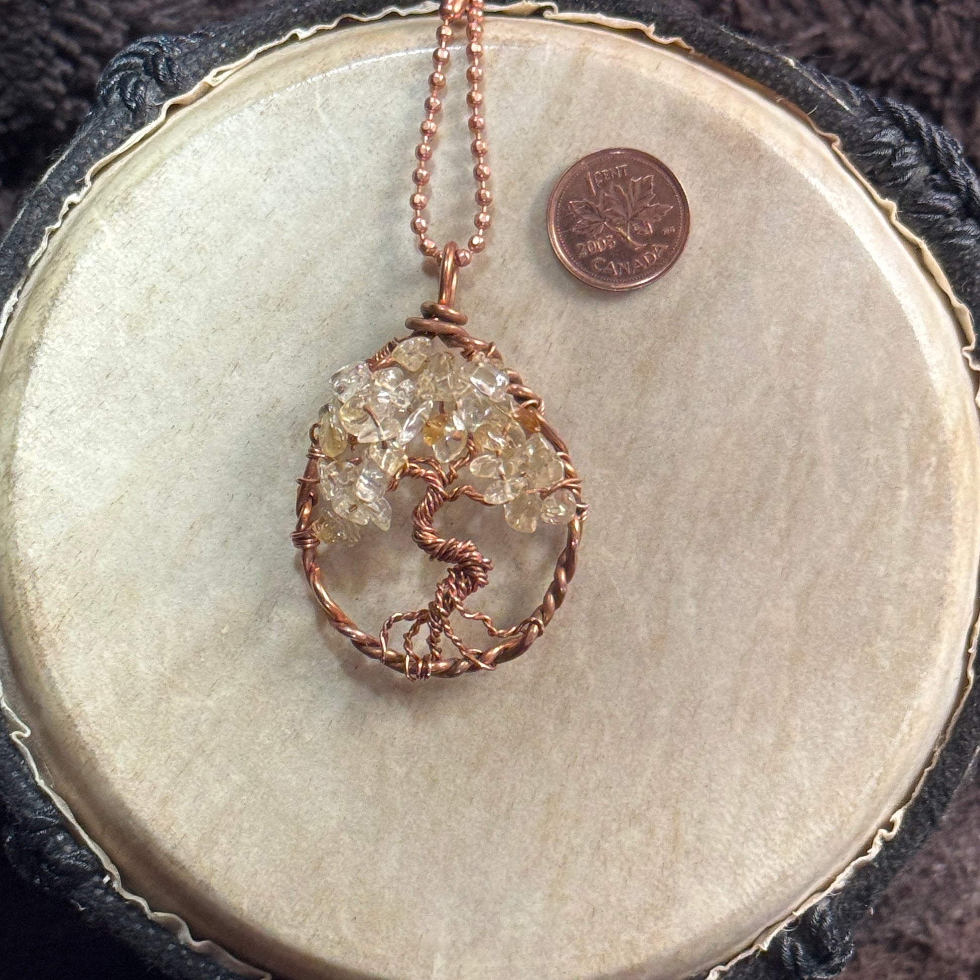 Citrine Tree of Life necklace formed inside a raw reclaimed copper teardrop, shown on a 20-inch faceted copper ball chain beside a penny.