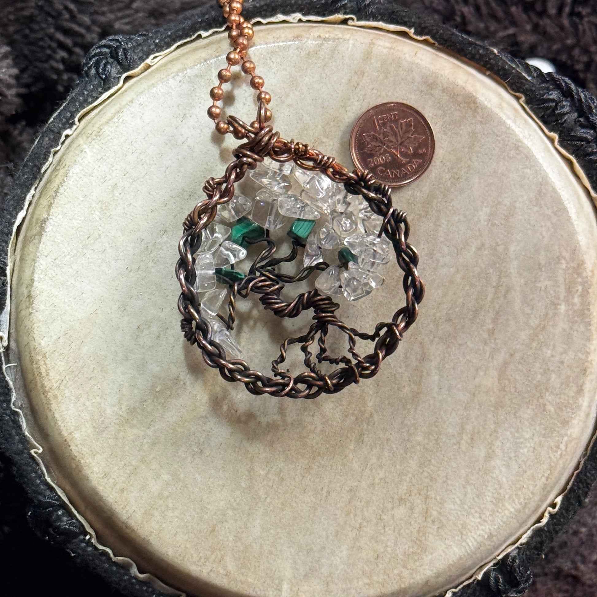 Reverse view of a malachite and clear quartz Tree of Life pendant showing its twisted copper trunk, exposed roots and faded ombré patina.
