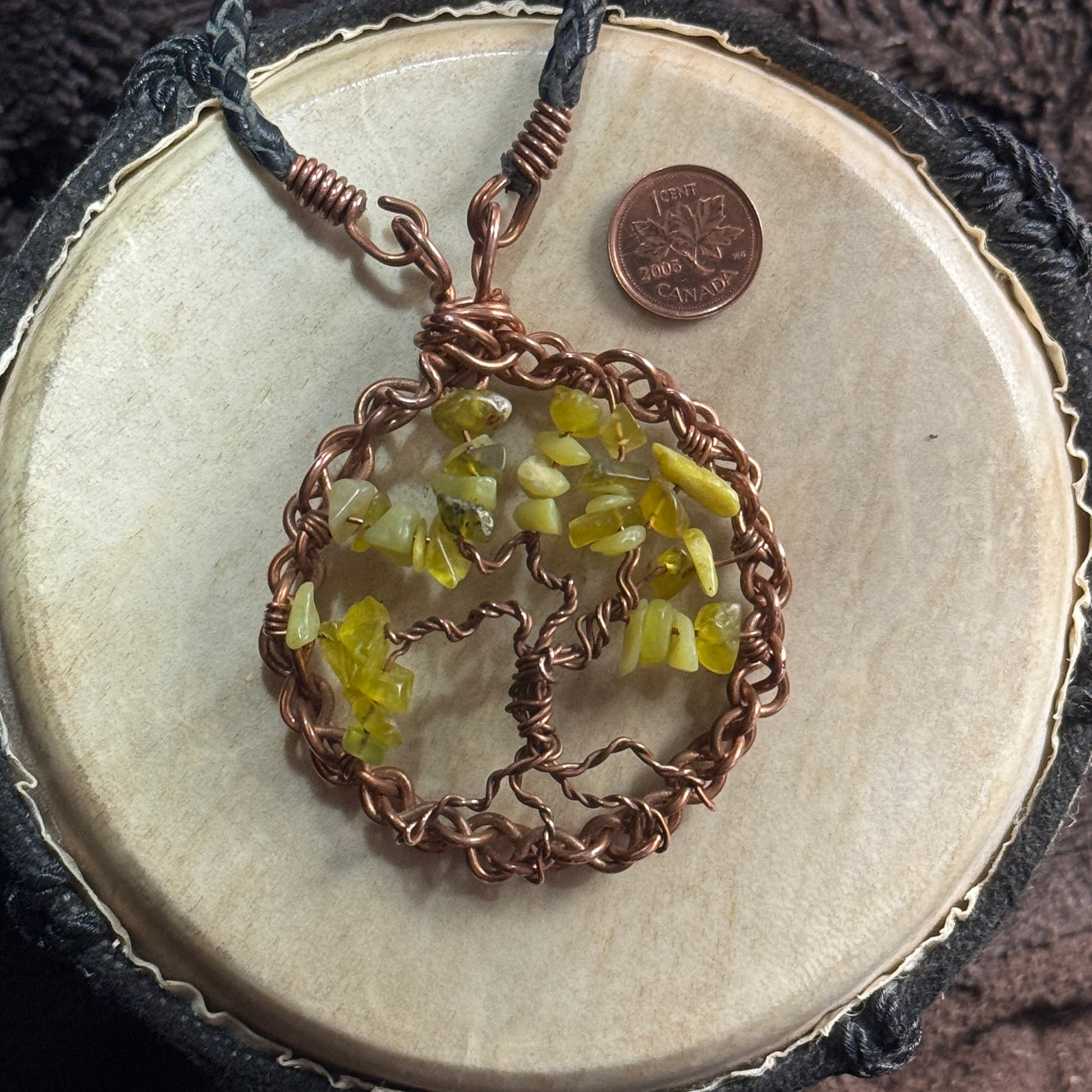 Close view of the front hook-and-loop clasp above a lemon jade and raw reclaimed copper Tree of Life pendant, shown with a penny for scale.