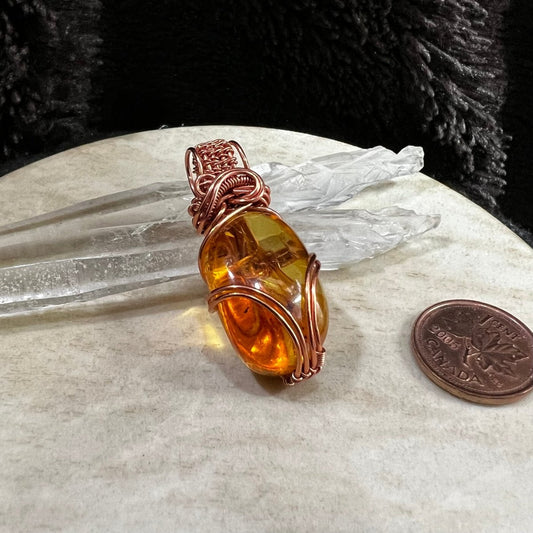 amber pendant wrapped in reclaimed copper with warm golden translucent resin stone, handmade one of a kind necklace on neutral background