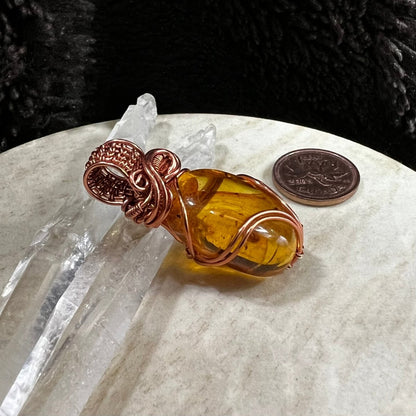 close up of amber stone wrapped in copper wire highlighting translucent honey tones and organic texture, handmade pendant