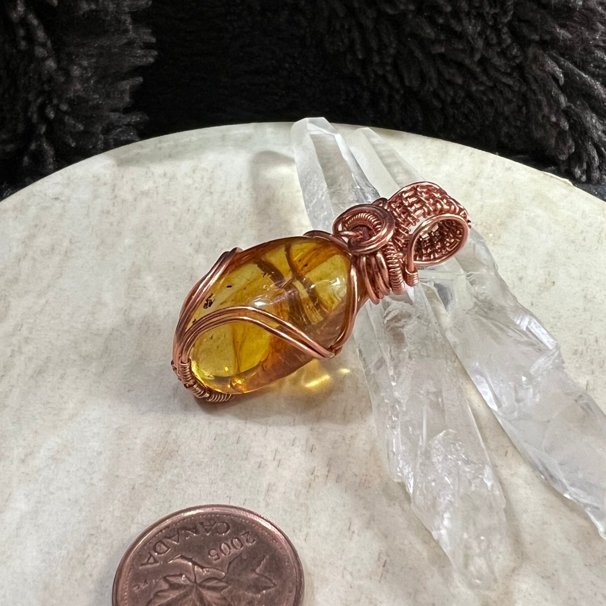 side view of amber pendant in copper wire wrap showing natural inclusions and golden glow, handmade artisan jewellery