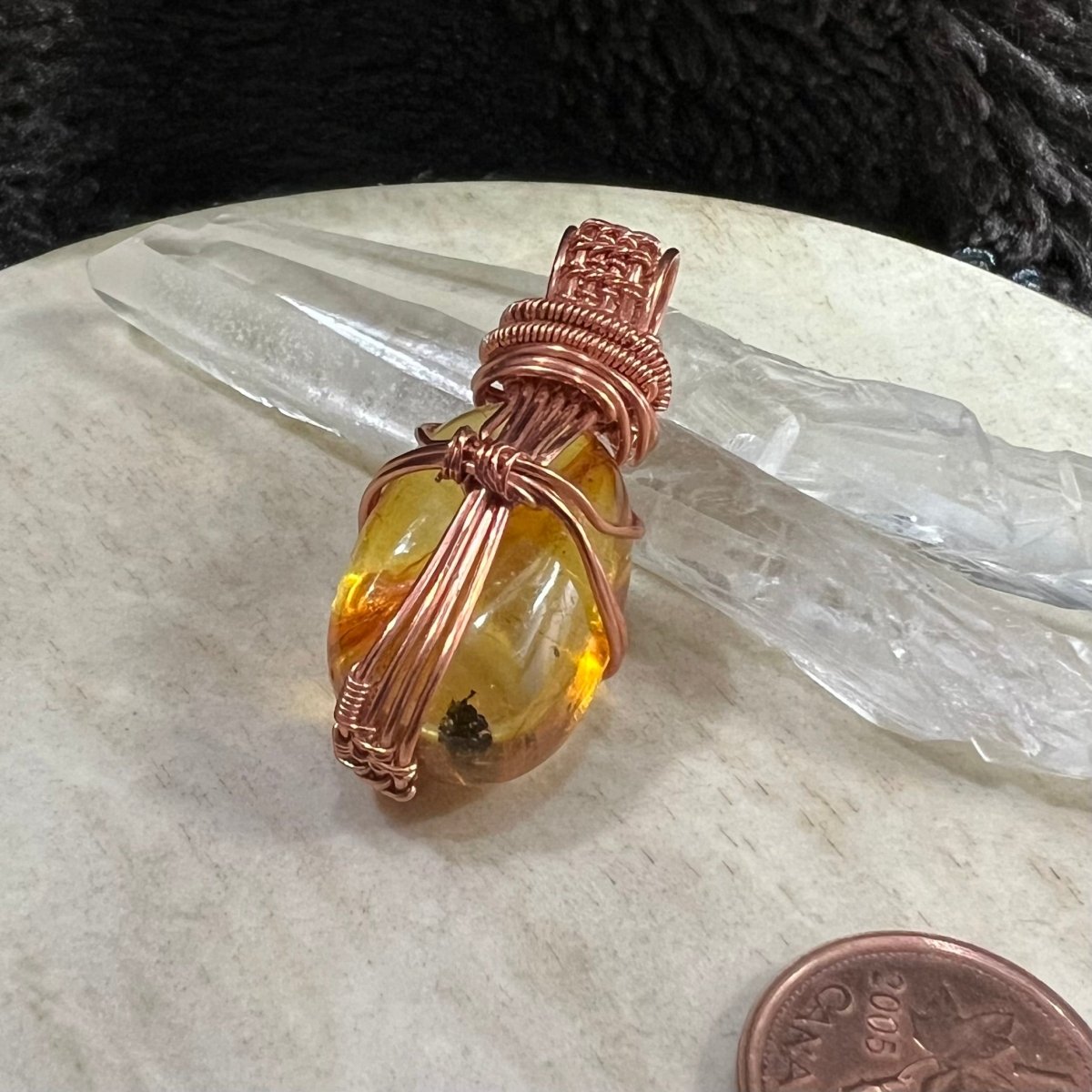 back view of handmade amber pendant showing copper wire wrapping structure and natural stone shape, artisan jewellery