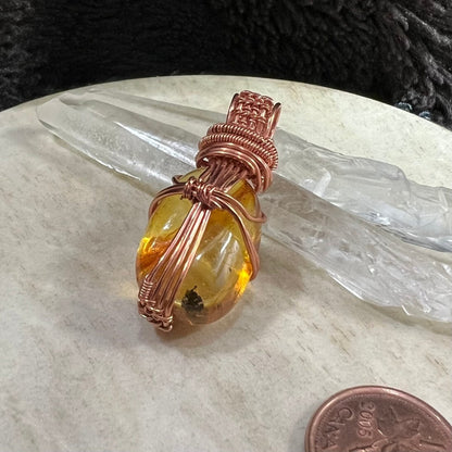 back view of handmade amber pendant showing copper wire wrapping structure and natural stone shape, artisan jewellery