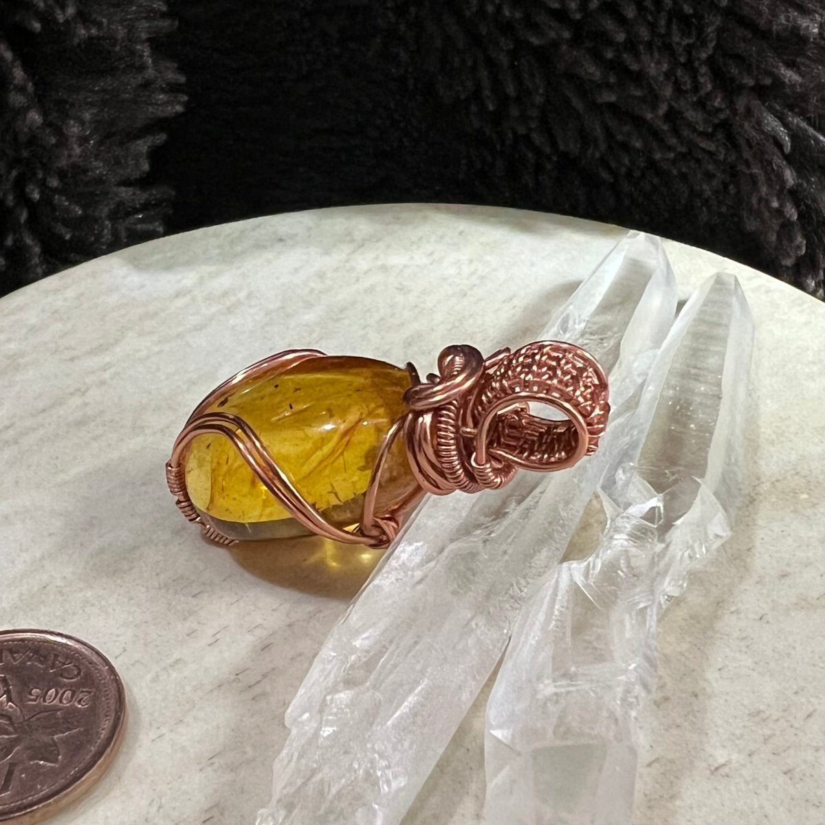 amber copper pendant beside coin for size reference, warm golden fossilized resin necklace handmade with reclaimed copper