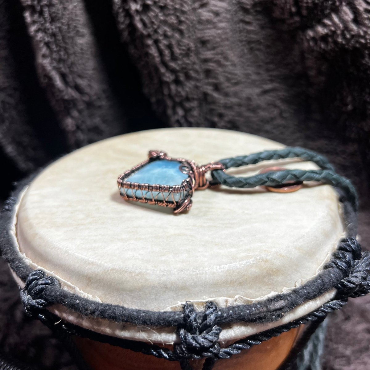 Necklace with a blue stone and braided design on a textured surface