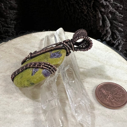 Side view of copper-wrapped Atlantisite pendant highlighting structural wire bands and handcrafted detail