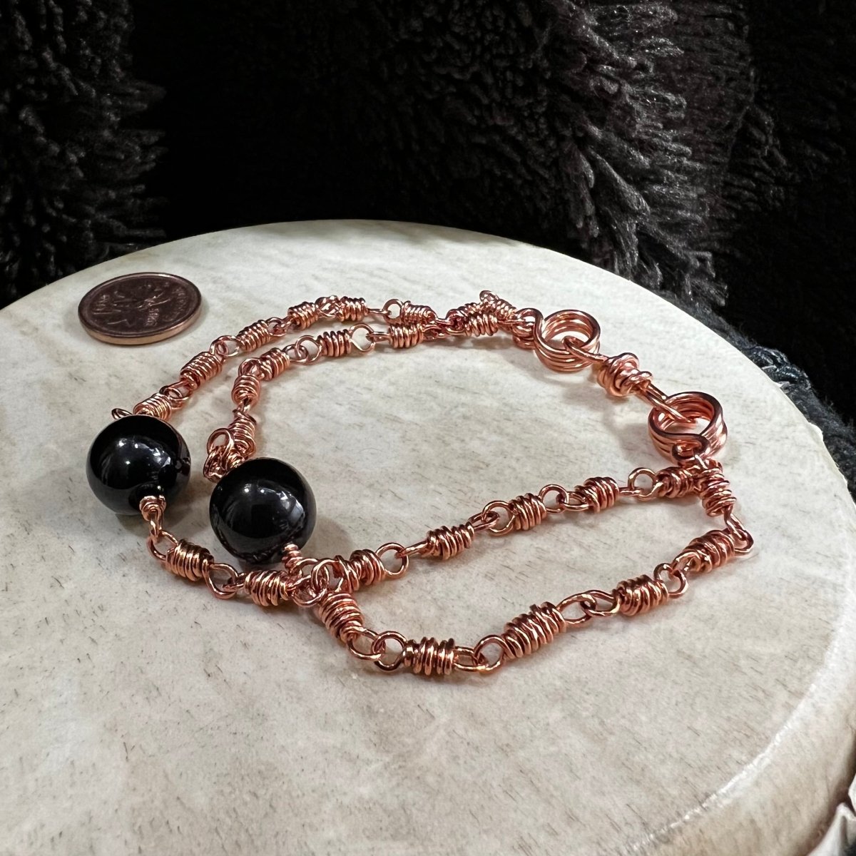 black agate double strand bracelet with reclaimed copper wire links and glossy black agate beads, handmade grounding protection bracelet on neutral background