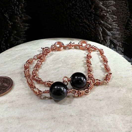 black agate double strand bracelet with reclaimed copper wire links and glossy black beads, handmade grounding protection bracelet on neutral background